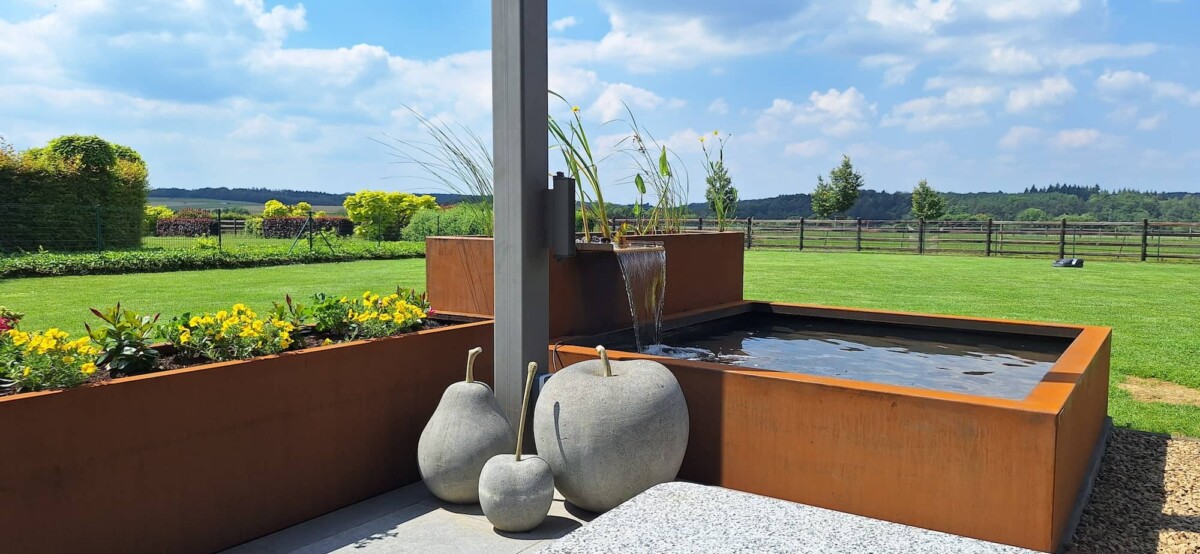 Vue de la terrasse sur un bassin en acier corten et sa lagune 